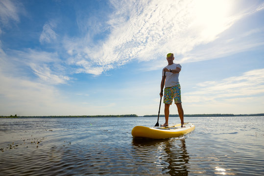 Joyful man is training  SUP board in large river