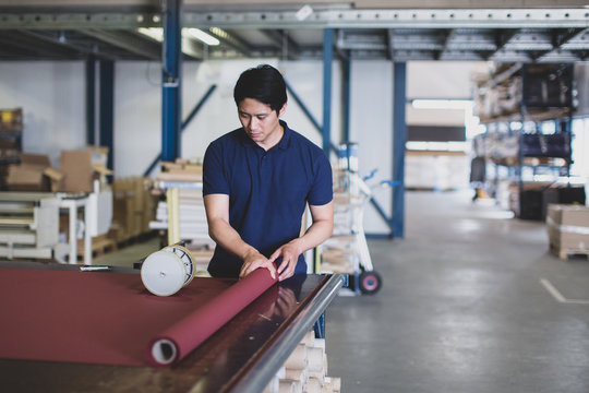 Male cutting fabric in a manufacturing warehouse