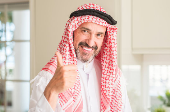 Middle age arabian man at home happy with big smile doing ok sign, thumb up with fingers, excellent sign