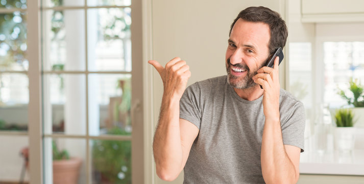 Middle age man using smartphone pointing with hand and finger up with happy face smiling