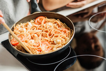 cropped shot of woman preparing delicious pasta on frying pan © LIGHTFIELD STUDIOS