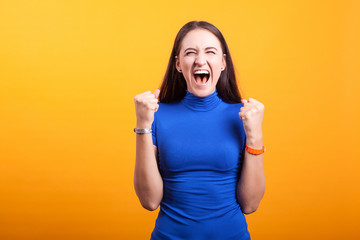 Angry woman yelling in studio over yellow backgound