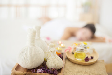 Fototapeta na wymiar Selective focus of Herbal compress balls with oil on the wooden table in spa salon and blurred background of woman lying on bed. alternative medicine and relaxation Concept.
