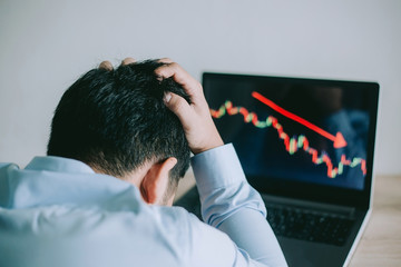 Stress Business man look at to the laptop show financial market chart graphic going down.  Stock...