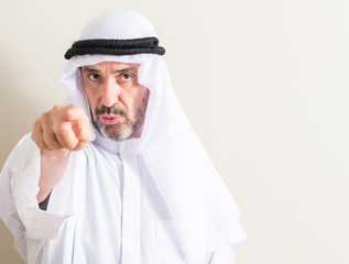 Senior arabic man pointing with finger to the camera and to you, hand sign, positive and confident...