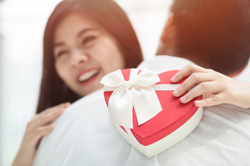 Selective focus Young Couple in Love, Man giving surprise Gift box  for beautiful young woman.
