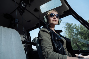 Ready to work. Cheerful female helicopter pilot waiting for a passenger while being ready to start a flight