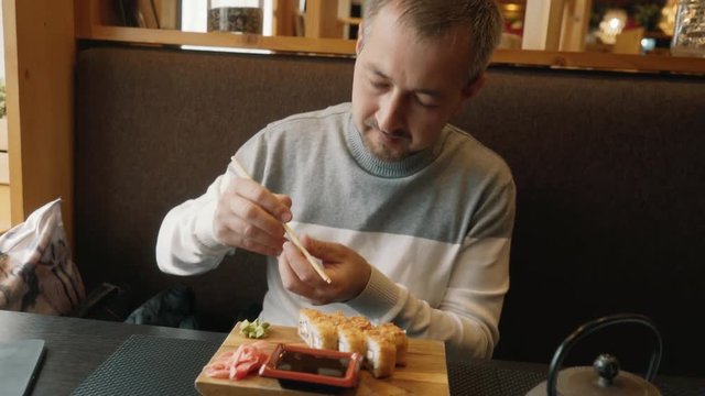 A man learns to use chopsticks for sushi. Hashi, chopsticks ohashi, varibasi - simple wooden hasi