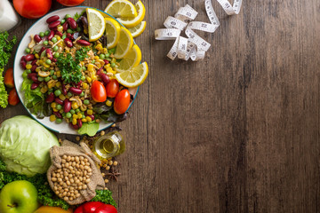 Healthy food background ,fruits and vegetables with salad bowl and measuring tape  on wooden table.