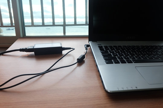 Plug in Adapter power cord charger of laptop computer On wooden floor