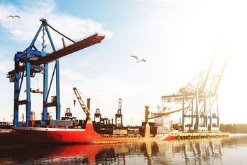 Fototapeta premium cargo ship at cargo terminal in harbor against blue sky