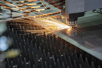 Close-up of the CNC laser cutting machine cutting the metal plate with the sparking light. Modern...