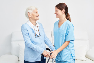 Krankenschwester unterstützt Seniorin mit Gehgestell