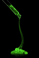 Cosmetic pipette with green transparent gel close up on black background