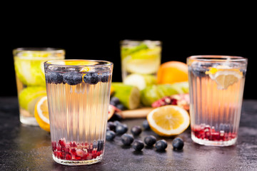Fruits, berried and vegetables next to glasses with detox water on vintage wooden background