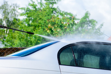 Naklejka premium Unidentified man worker washing car under high pressure water ou