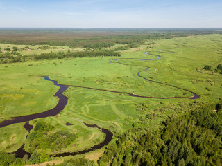 Beautiful aerial view of meandering river with bright green fiel