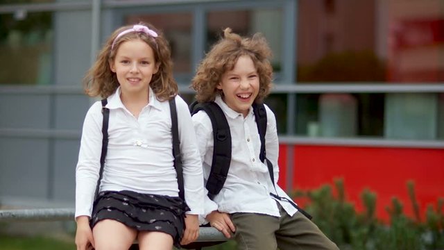 The boy and the girl are fooled after finishing school at school. First day at school, fooling around, happy schoolchildren