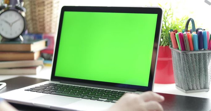 Over the shoulder view of  young boy watching on laptop computer . Green screen of technology being used. Chroma Key laptop. Dolly move left to right.