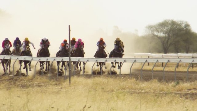 A full shot of horse riding racing in slow motion. Camera tracks the movement of the racers.