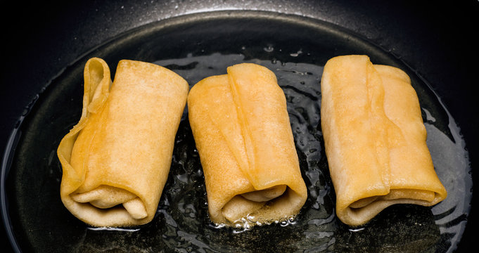 Three pancakes in boiling oil in a frying pan