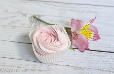 Розовый клубничный зефир на светлом фоне с цветком орхидеи