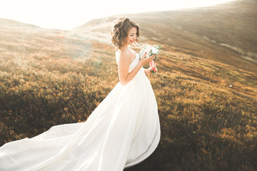 Fototapeta na wymiar Beautiful bride with a bouquet on mountain background at sunset
