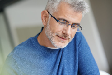 Middle-aged guy with trendy eyeglasses reading newspaper