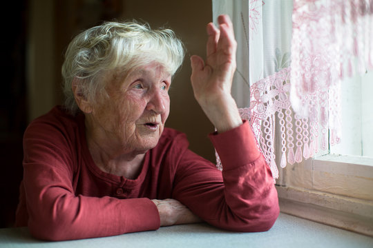 Russian elderly woman emotionally talking sitting at a table at the home.