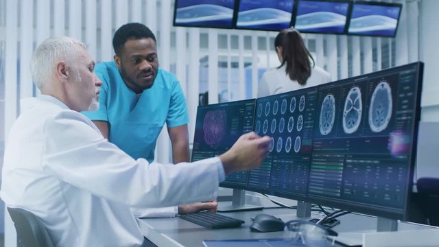 Medical Scientist and Surgeon Discussing CT / MRI Brain Scan Images on a Personal Computer in Laboratory. Shot on RED EPIC-W 8K Helium Cinema Camera.
