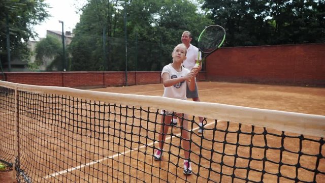 Coacher teaching young girl to playing tennis.