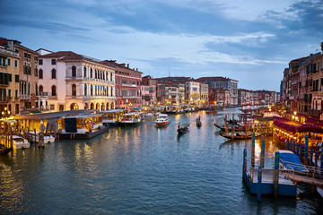 Canal Grande with boats and lights in Venice at Sunset. Next to famous Rialto Bridge and the Street "Riva del fin" - Italy