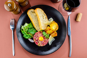 Raw tasty beef tartare with egg yolk and toasts on the plate in 