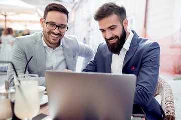 Two men working on laptop in cafe