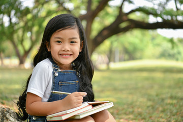Education Concepts. The girl is reading a book in the garden. Beautiful girl is seriously studying. Beautiful girls are happy learning.