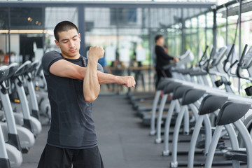 Fototapeta na wymiar Asian fitness man warm up by stretching arms before exercises at the gym. copy space.