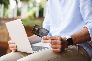 Cropped photo of man outdoors using laptop