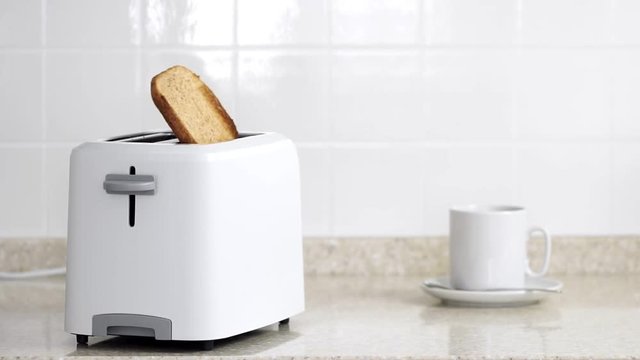 Roasted toast bread popping up from white modern toaster machine.