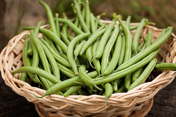 Green pods of fresh asparagus beans In a wooden wicker basket.