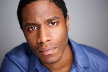 Obraz premium Close up serious young african american man against gray background