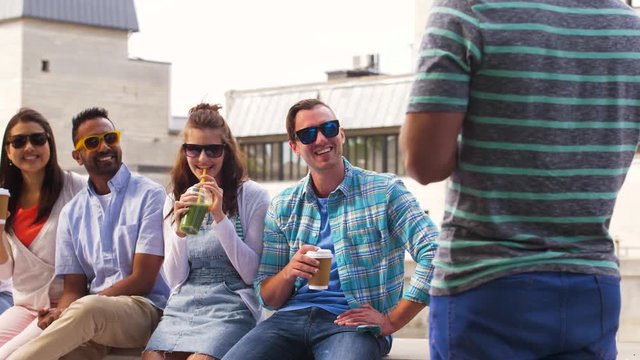 people, friendship and international concept - group of happy friends drinking coffee and juice talking in city