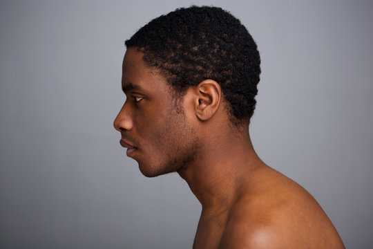 side portrait of shirtless african american man against gray background
