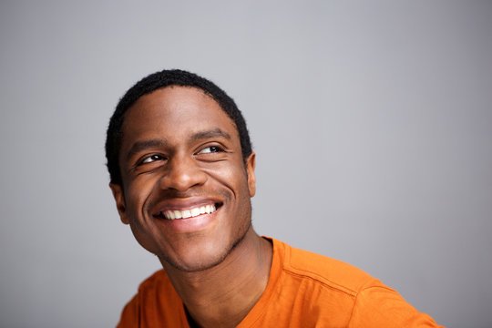 happy african man smiling and looking up against gray background