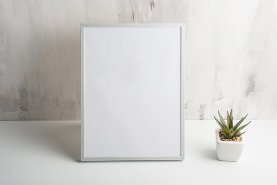 Empty white frame with flower on wall background. The concept of design and font inscriptions and image placement