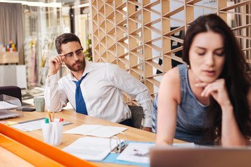 Great shapes. Inspired handsome man sitting at the table and checking out his worker