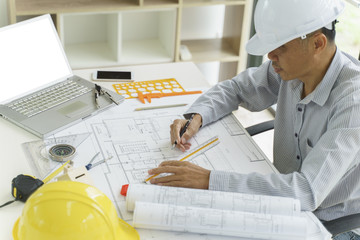 Architect or engineer hands working on blueprint plans  with a pencil and laptop a ruler,...