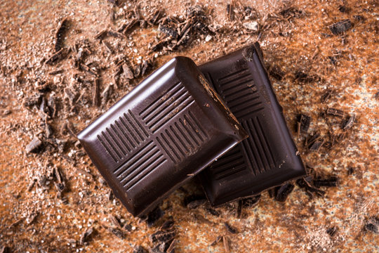 Black chocolate pieces on brown background. 