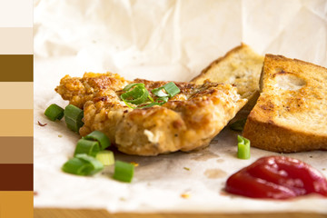 Fresh fried pork chops sprinkled with green onions and ketchup.  Arrangement  on the wrapping paper  with color palette