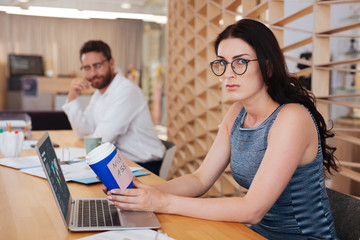Harassment. Surprised pretty woman sitting at the table and holding a cup with a sticker