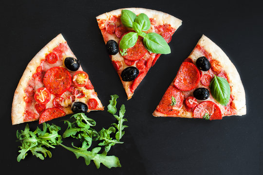 Slices of Traditional Italian Pepperoni  pizza on a black background with  Space for text. Pizza menu. Top view